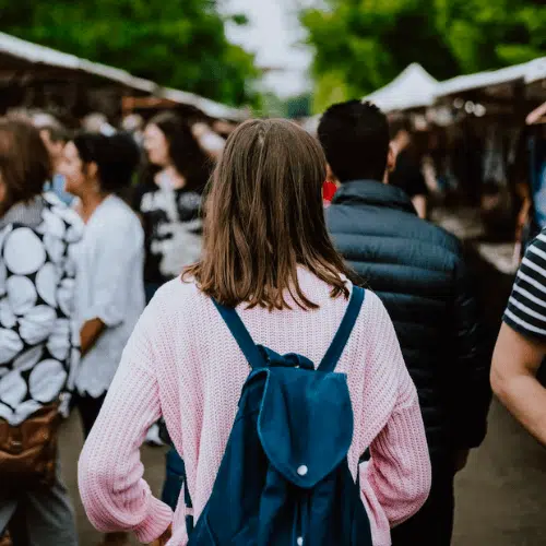 Woman walking through a crowd with a backpack on