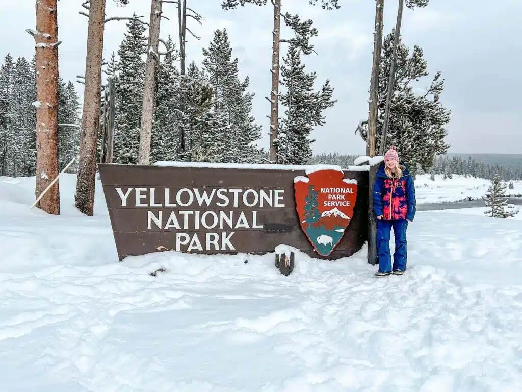 Jackie in front of the Yellowstone National Park sign in Wyoming