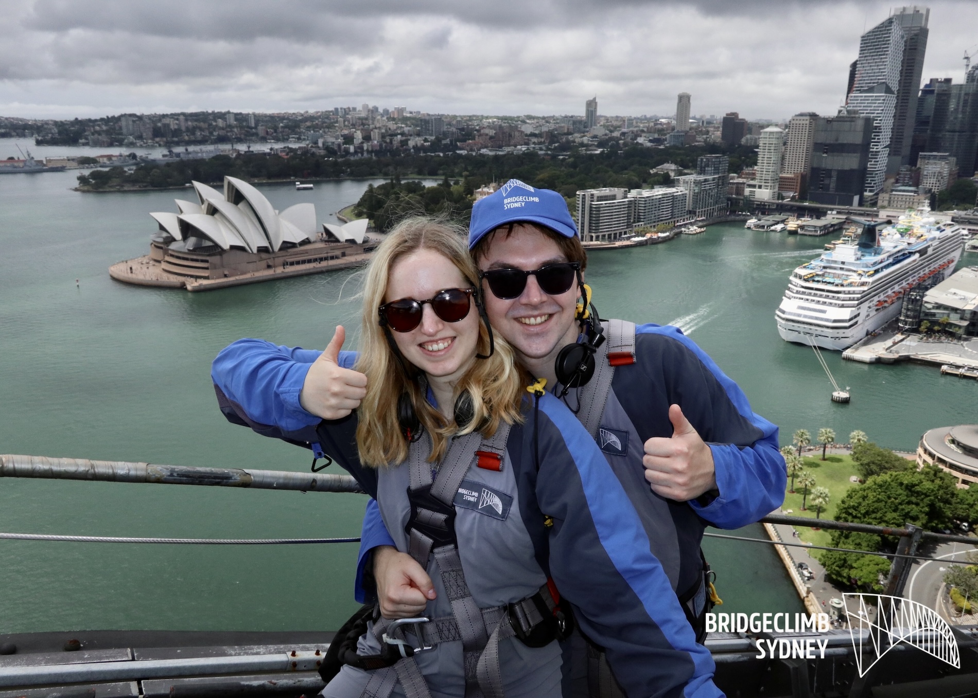 The author and her husband giving a thumbs up at the top of the Sydney Harbour Bridge overlooking the Sydney Opera House