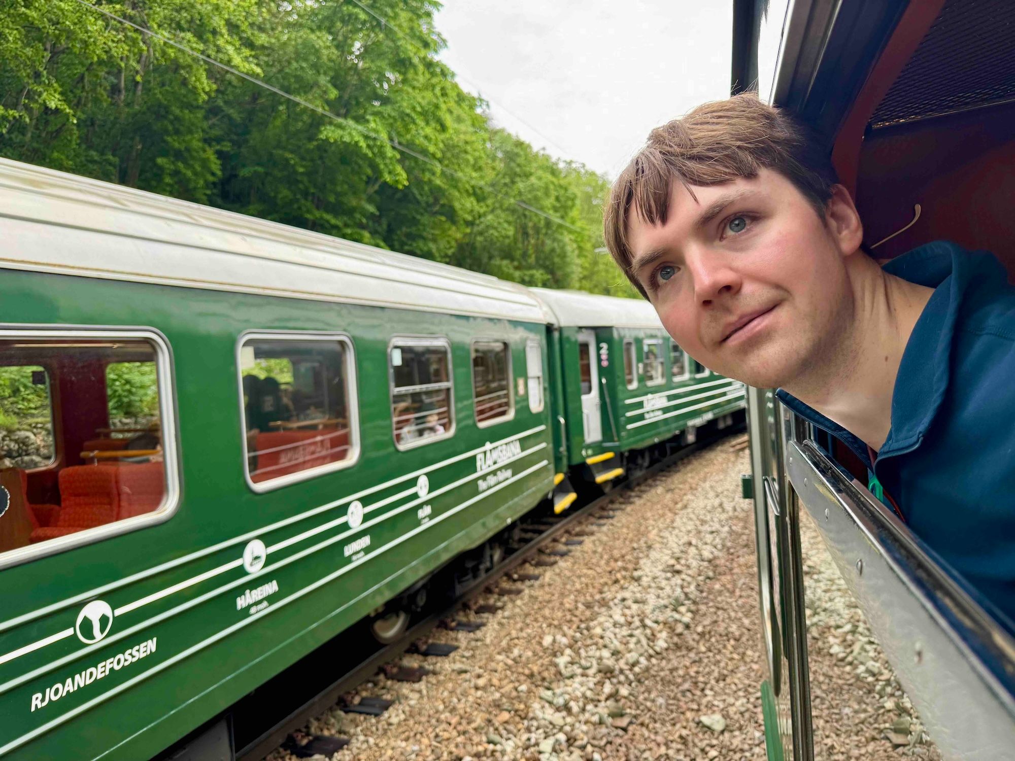 man sticking his head out the window on the Flåm railway
